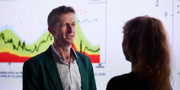 andrew turpin in front of projected graph talking to interviewer