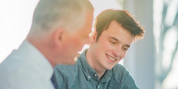 young man at desk in conversation with older man